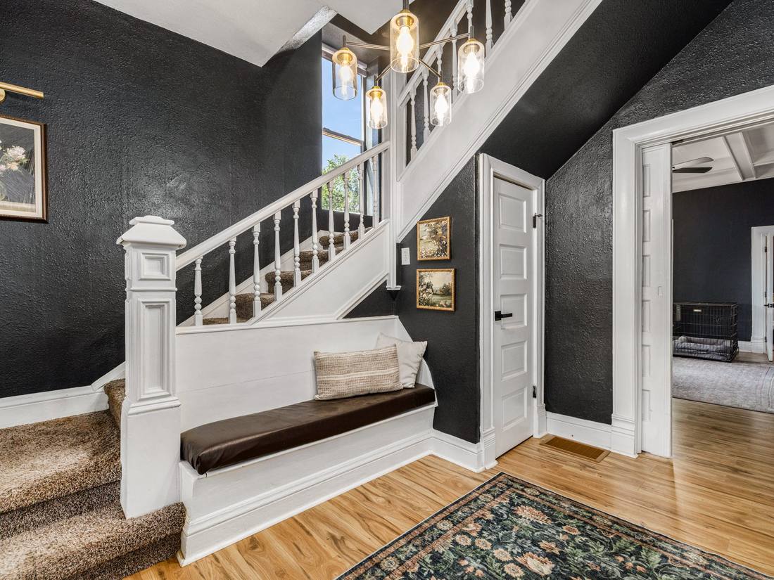 Entry hall with charcoal walls, a white staircase and built-in bench