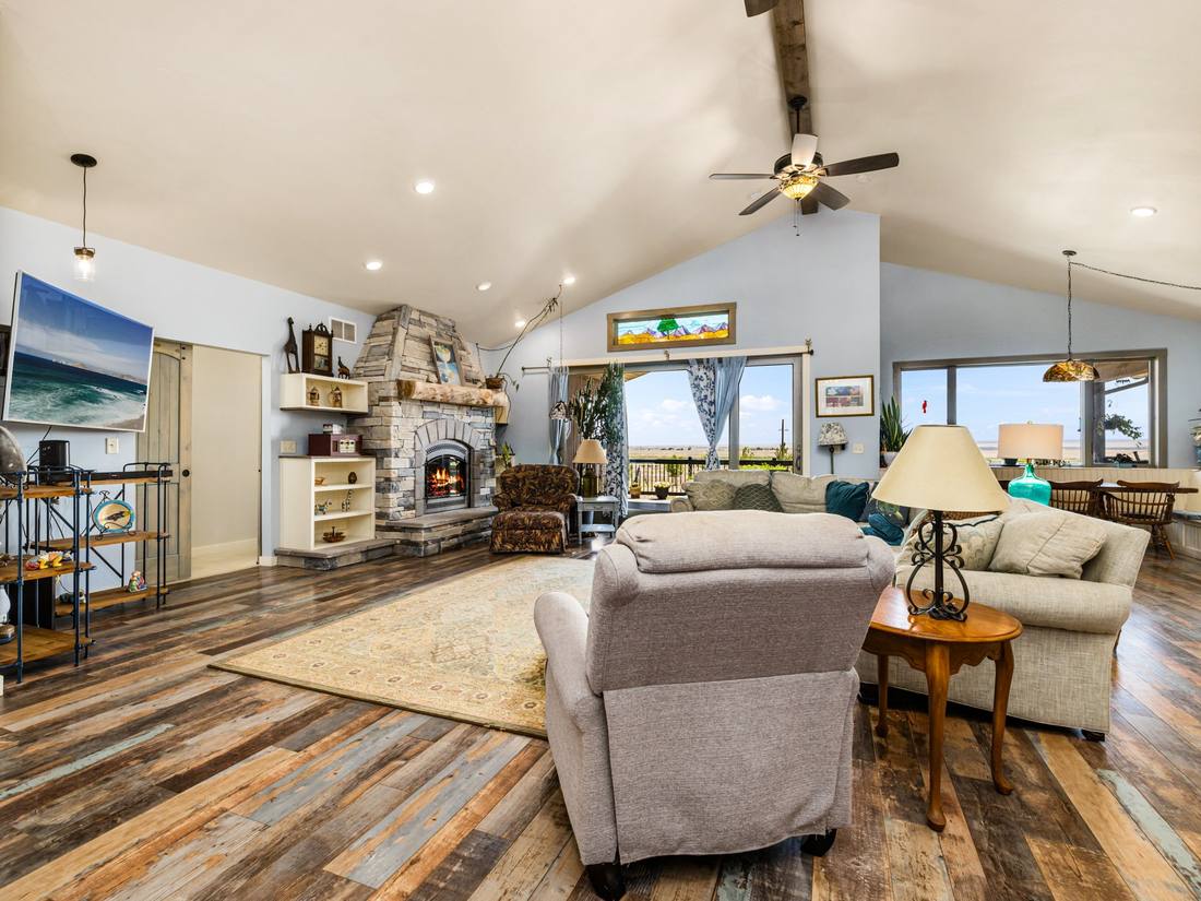 Great room with a lit stone fireplace under a vaulted ceiling